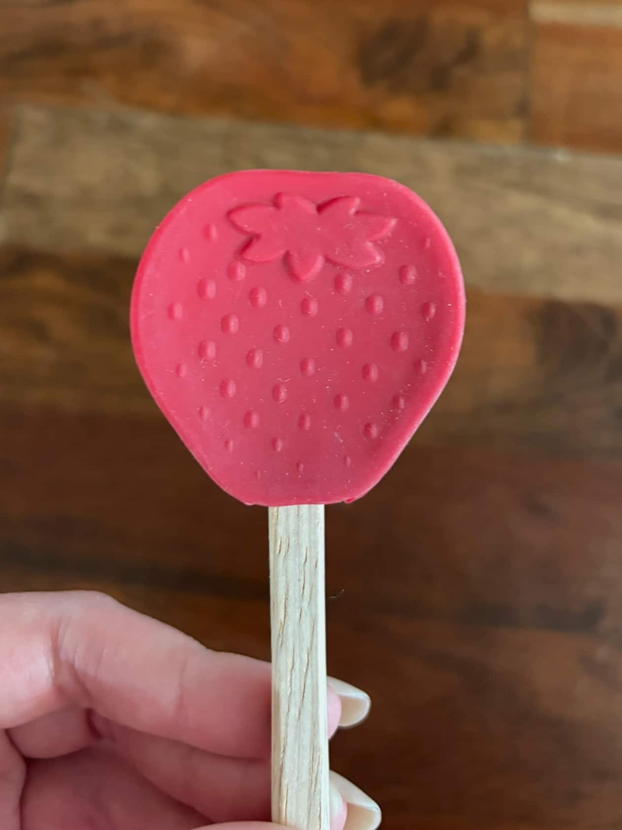 Small strawberry-shaped silicone spatula with wooden handle for baking and cooking.