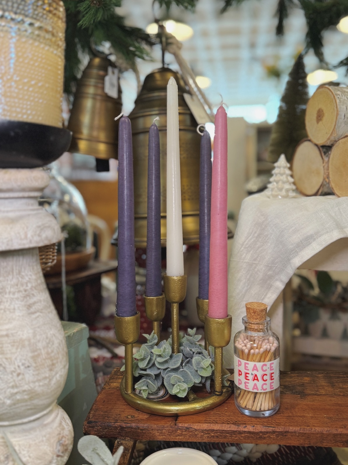 Gold Advent Candle Holder with purple, pink, and white taper candles styled with eucalyptus greenery and a jar of Peace Mini Apothecary Matches.