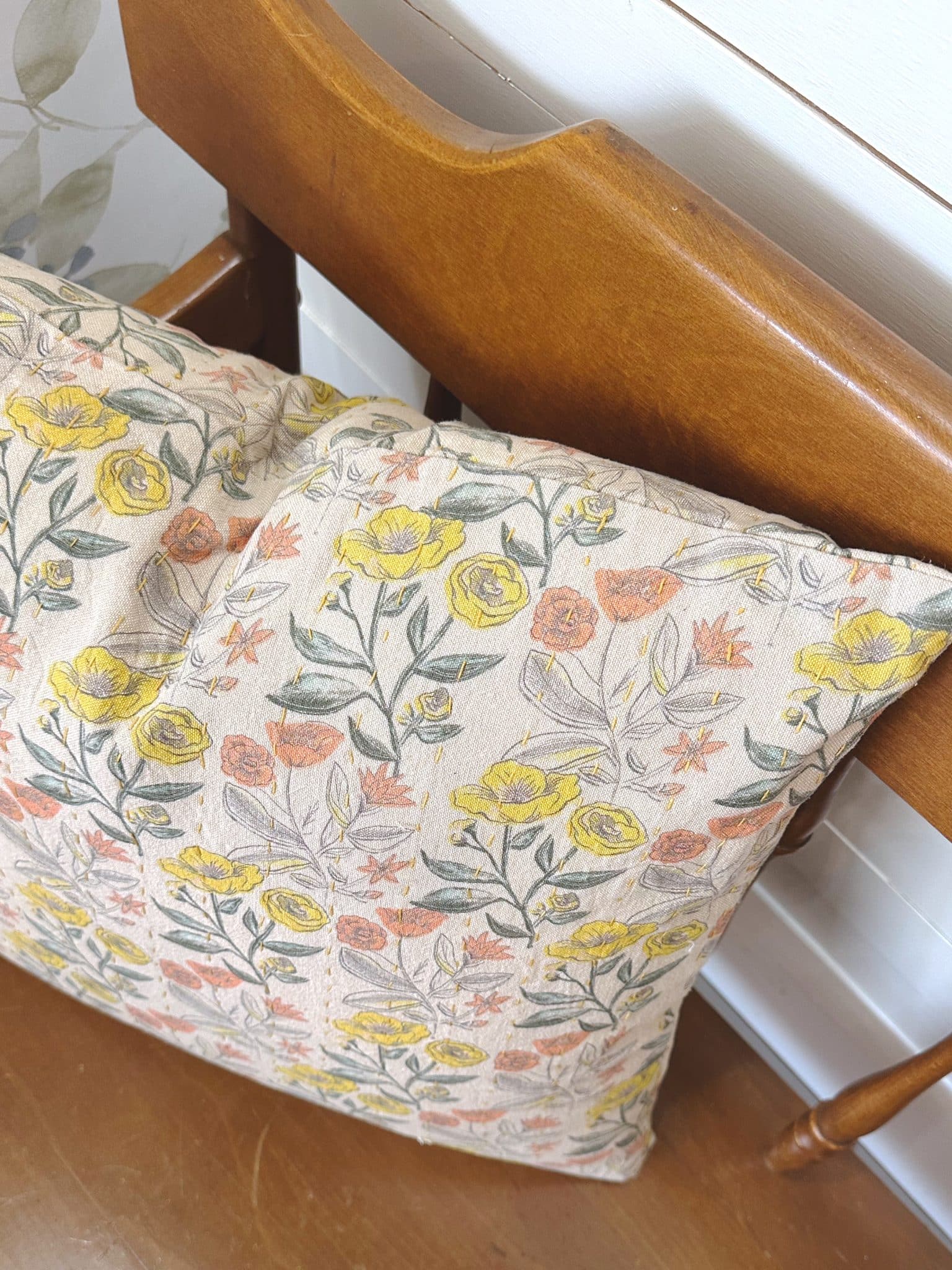 Close-up of the Cotton Chambray Floral Printed Throw Pillow featuring a vintage-inspired floral design in yellow, peach, and muted green on a natural background.