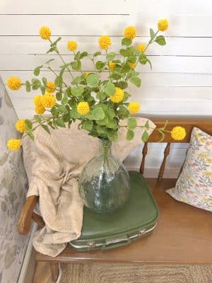 Large green bubbled glass vase with curved silhouette and textured finish, styled on a wooden bench.