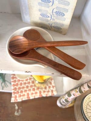 three carved acacia wood spoons styled in a ceramic dish on a shelf