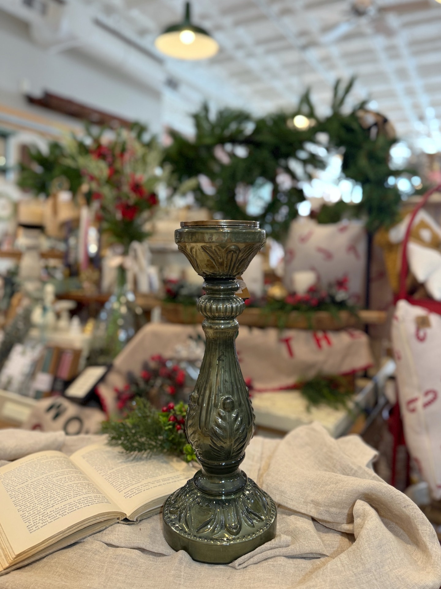 Green embossed mercury glass pillar candle holder with intricate vintage detailing and reflective finish on a table display.