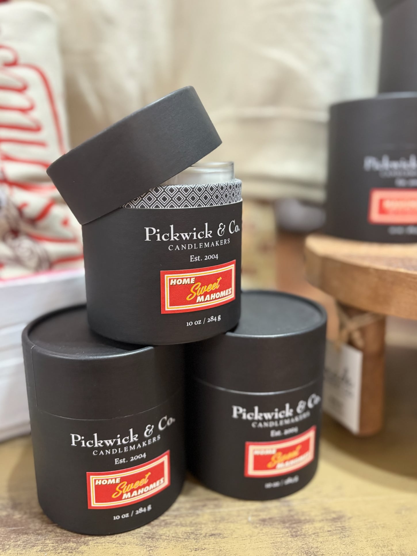 be-made-hays-ks-home-sweet-mahomes-pickwick-candle Pickwick & Co. Home Sweet Mahomes candle in a black gift box with the lid open, styled among stacked candle boxes.