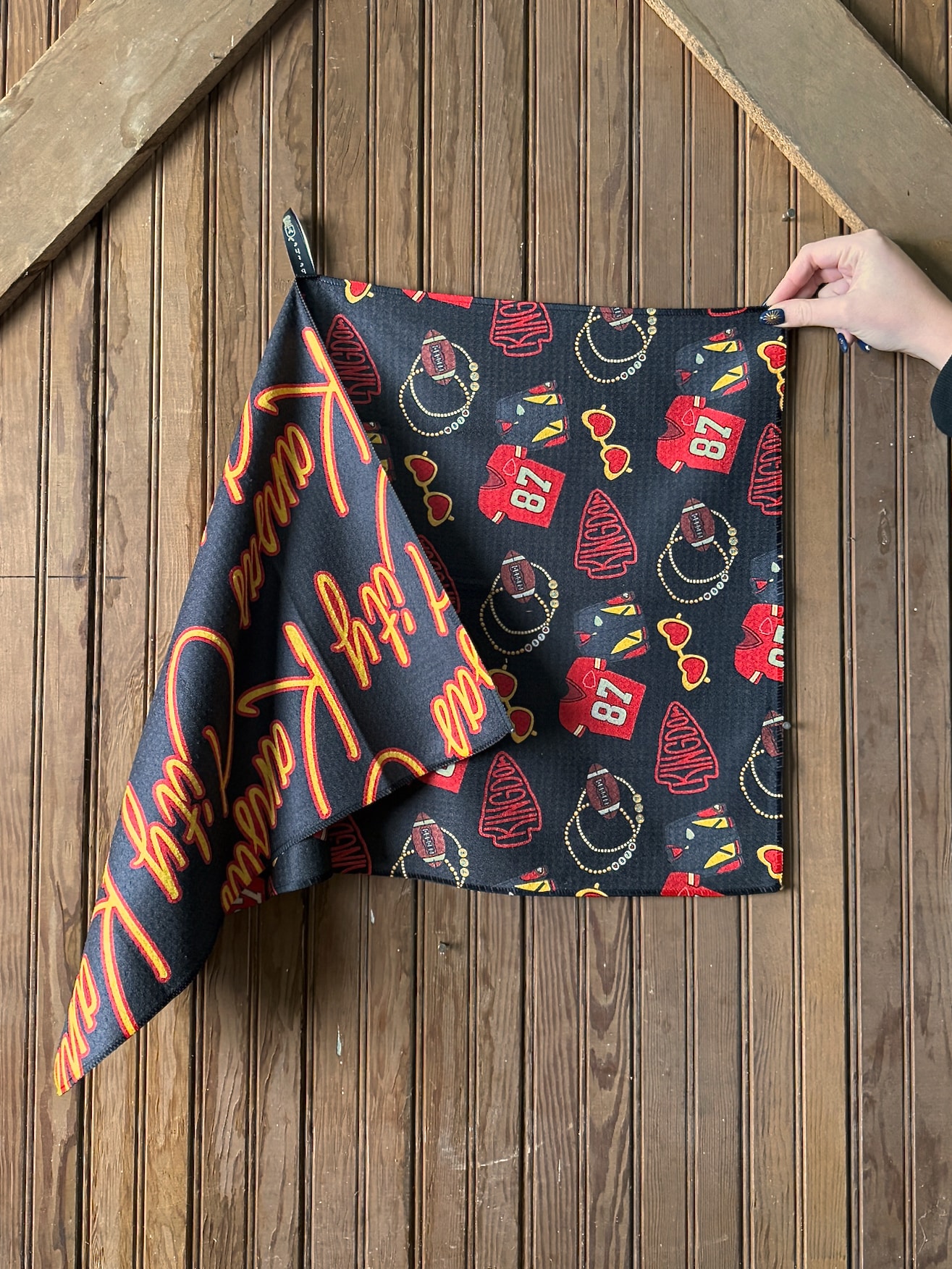 Double-sided Chiefs-themed microfiber tea towel shown flat and folded, featuring “Taylor’s Boyfriend” lettering and red and gold football icons on a dark background.