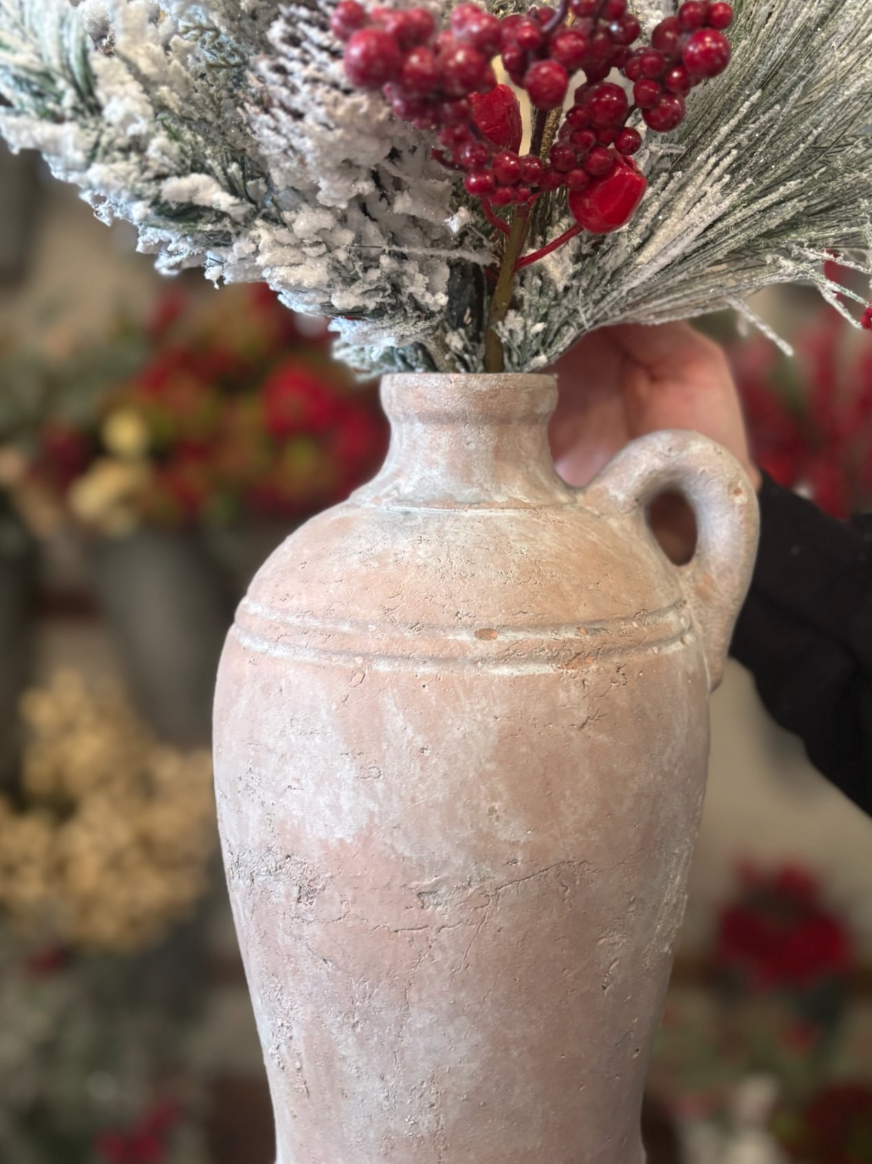 A close-up of the tuscan terracotta vase showing its weathered texture and winter floral arrangement.