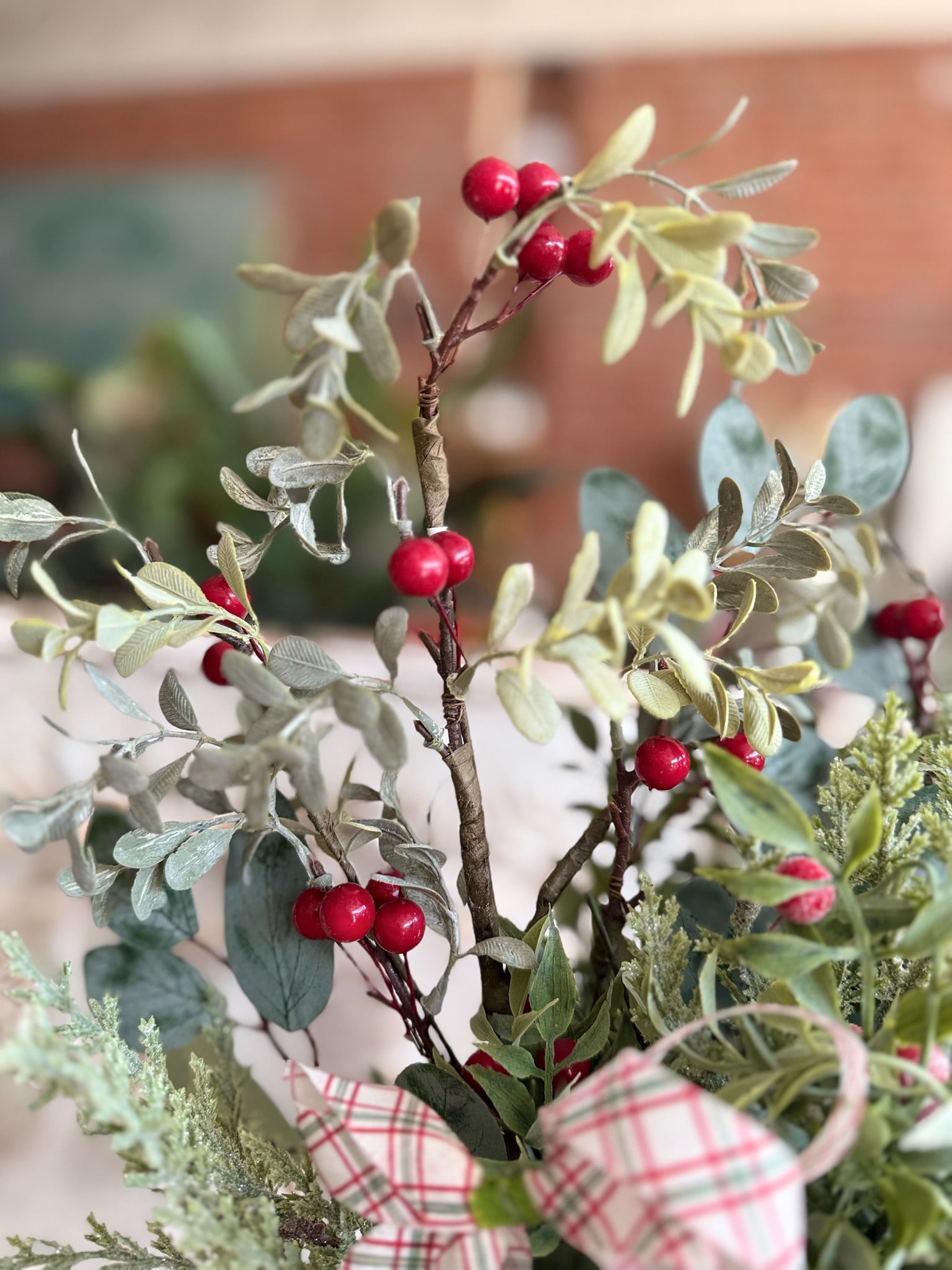 Eucalyptus and Berries Floral Pick featuring soft green eucalyptus leaves and bright red berries with a plaid bow accent.