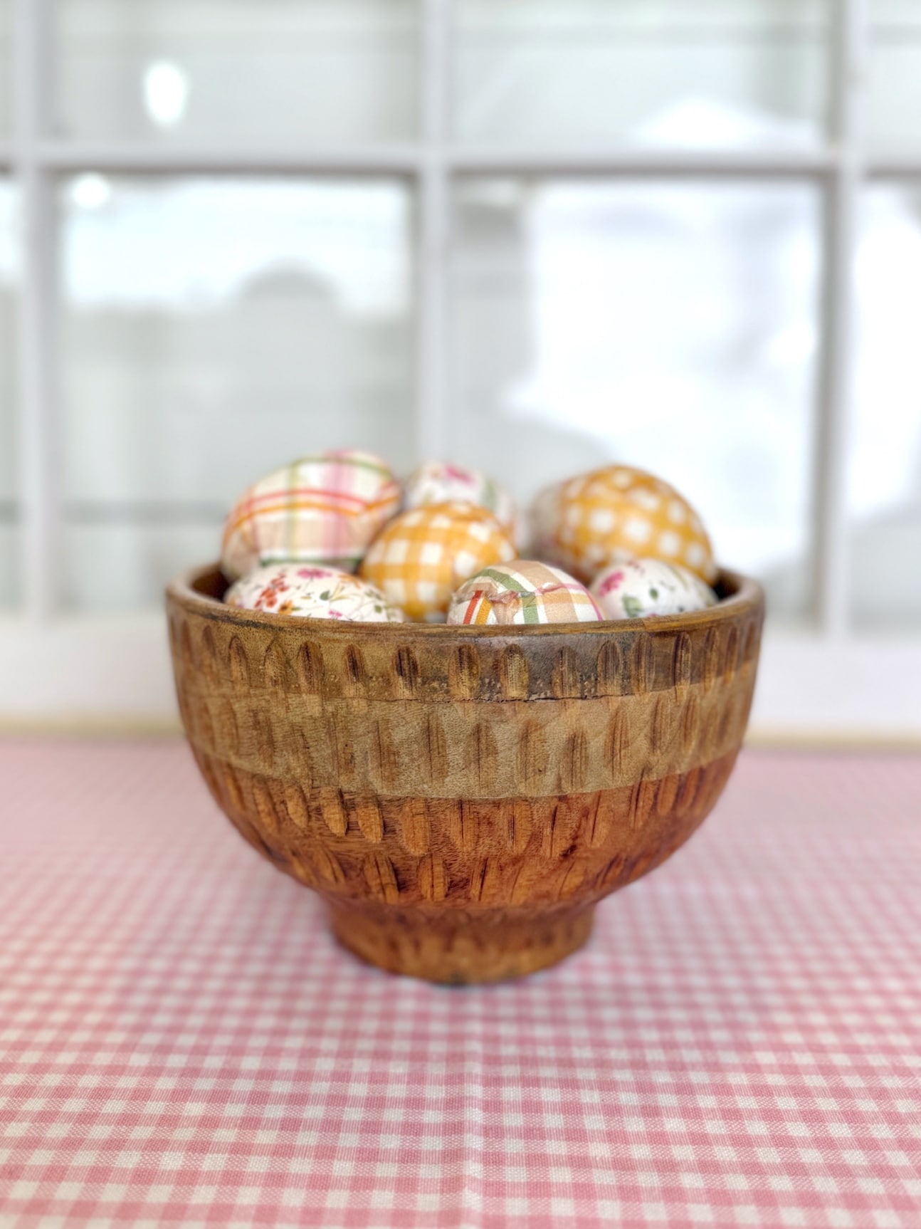 Spring gingham wooden eggs arranged inside textured footed wood serving bowl.