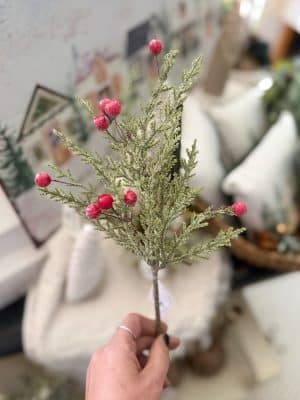 Glittered Pine Berries Floral Pick with frosted pine greenery and red glittered berries held in hand for scale.