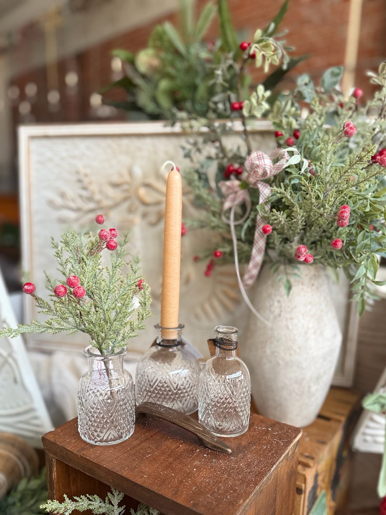 be-made-hays-ks-glittered-pine-berries-pick-and-pressed-glass-bud-vases-display Pressed glass bud vases with a glittered pine berries floral pick and a neutral taper candle, styled with frosted greenery and holiday accents.