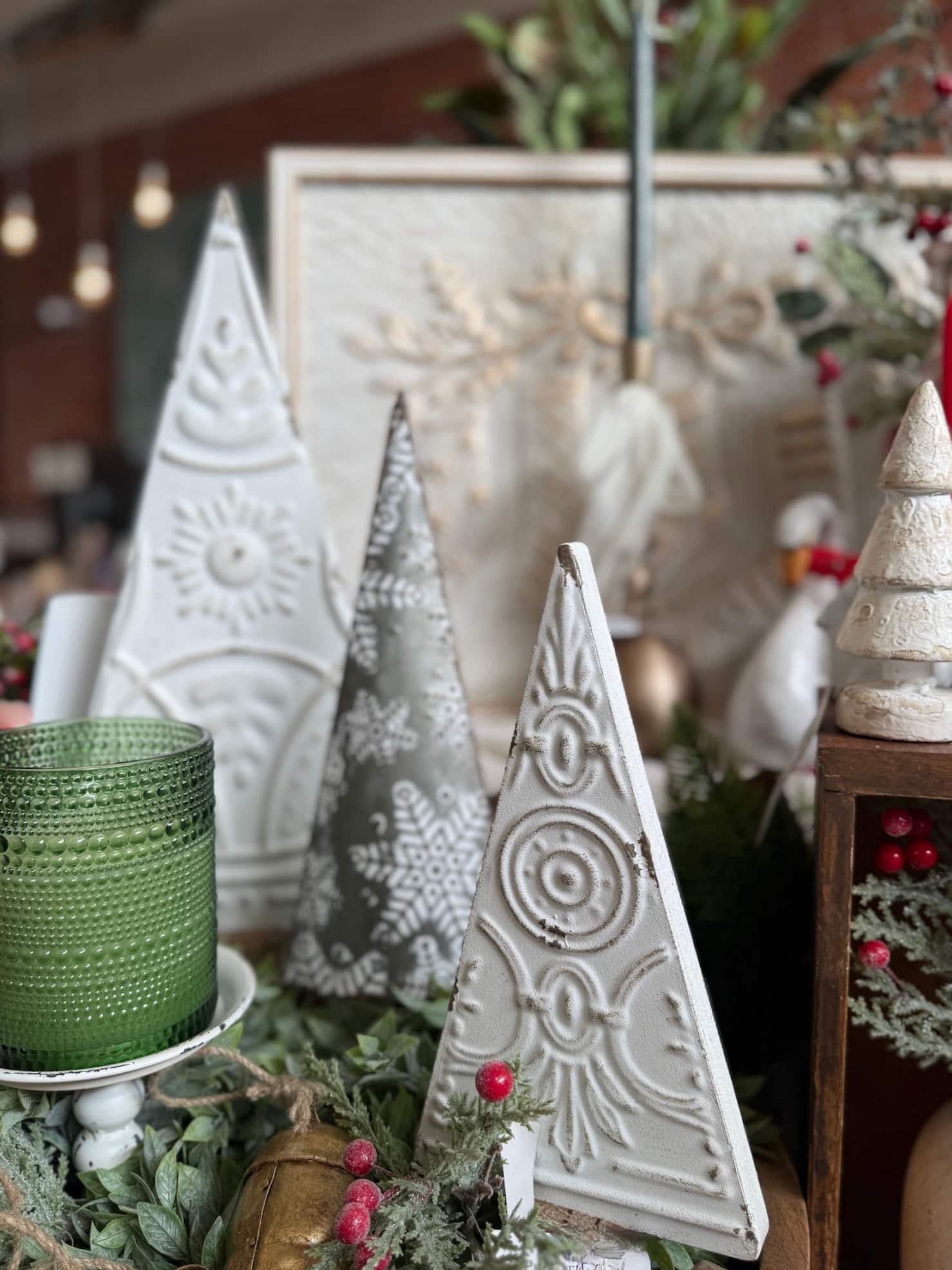 Antique White Pressed Metal Trees with embossed patterns styled alongside a silver snowflake tree, green candle, and holiday greenery.