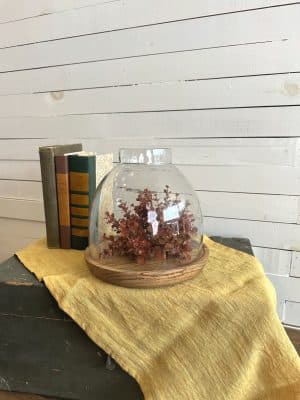 Side angle of fall table decor with glass candle cloche, styled on a textured mustard table runner.