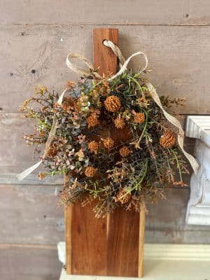 Autumn floral candle ring with textured blooms displayed on a rustic wood serving board