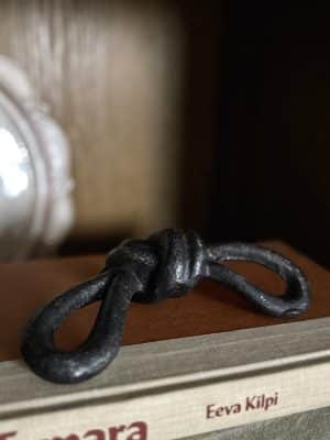 Close-up of a black cast iron sailor knot decor piece resting on a brown book.