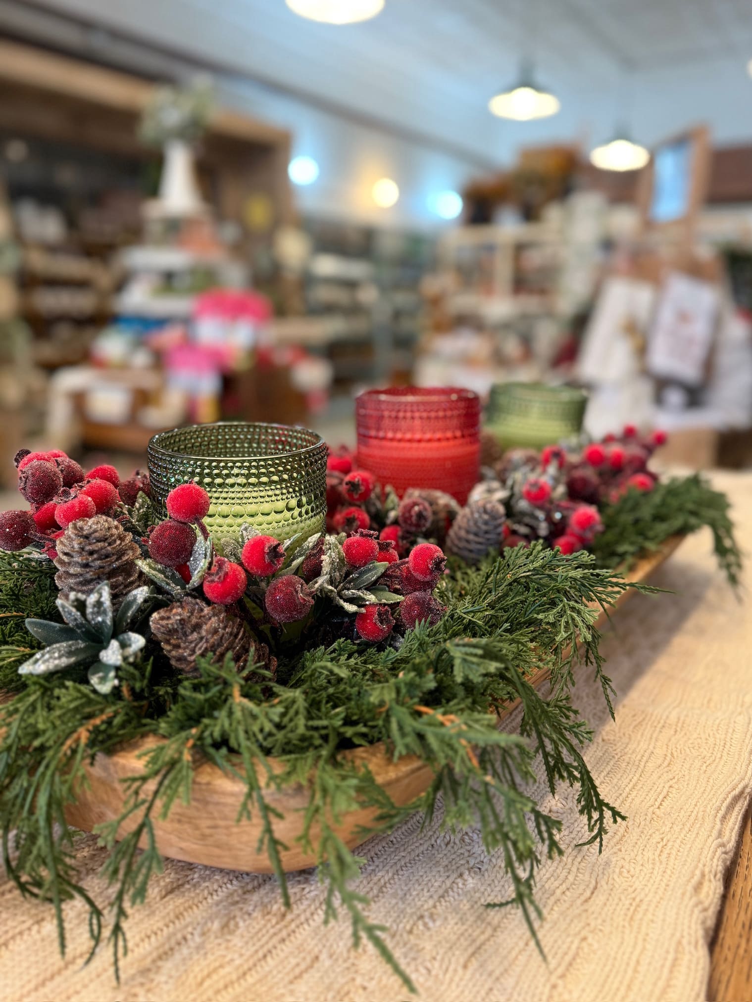 Close-up of frosted berry candle rings arranged in a large wood dough bowl with green and red dotted glass candles.
