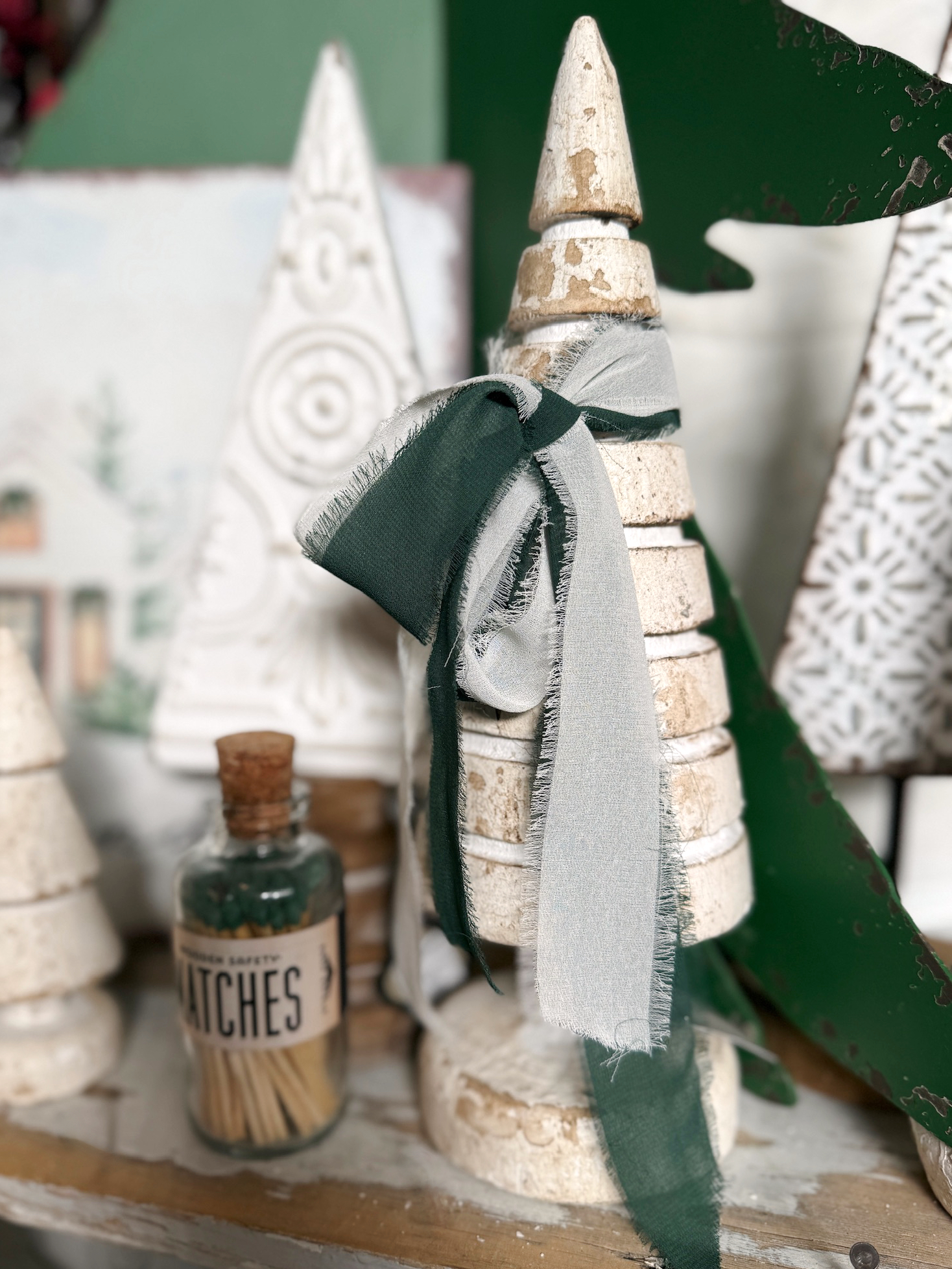 Close-up of the large Rustic Whitewashed Wood Tree with a whitewashed distressed finish, styled with layered chiffon ribbon and holiday accents.