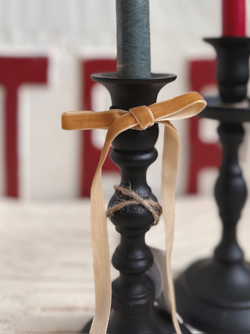 Close-up view of the Black Empire Taper Candle Holder Small showcasing the matte black cast-iron finish and tied tan velvet ribbon accent.