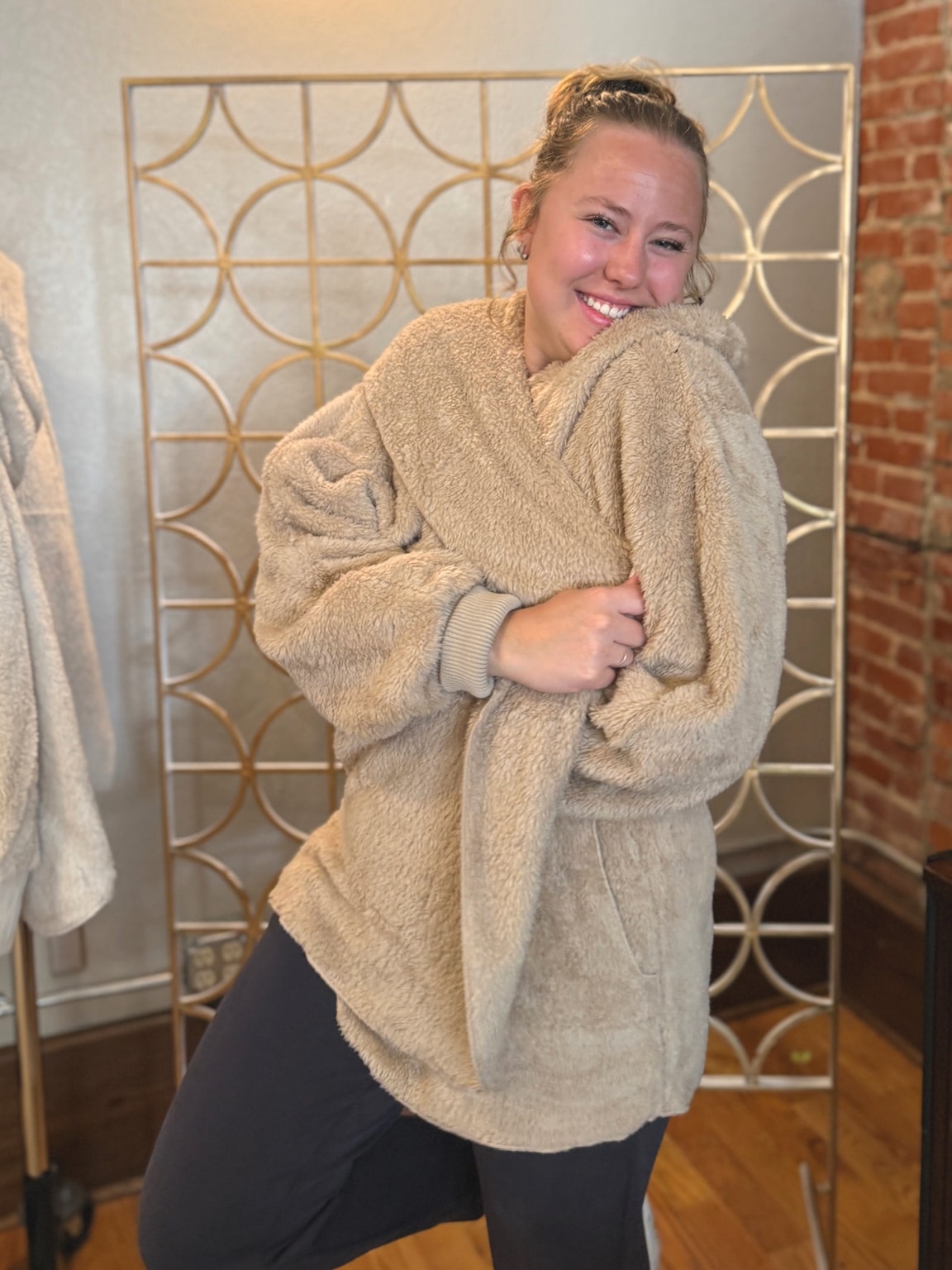 Taupe Plush Fur Hooded Jacket styled with pockets and oversized plush sleeves.