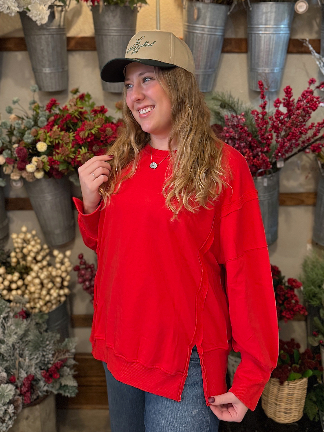 Oversized red crewneck with washed terry texture and side slits, worn casually with denim.