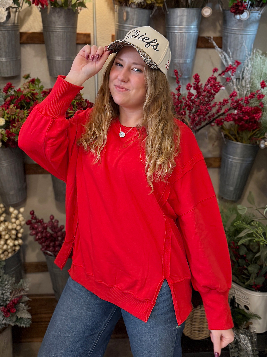 be-made-hays-ks-oversized-side-slit-crewneck-red-and-leopard-bill-chiefs-trucker-hat Woman wearing an oversized red crewneck with side slits and a natural-colored Chiefs trucker hat with a leopard-print bill.