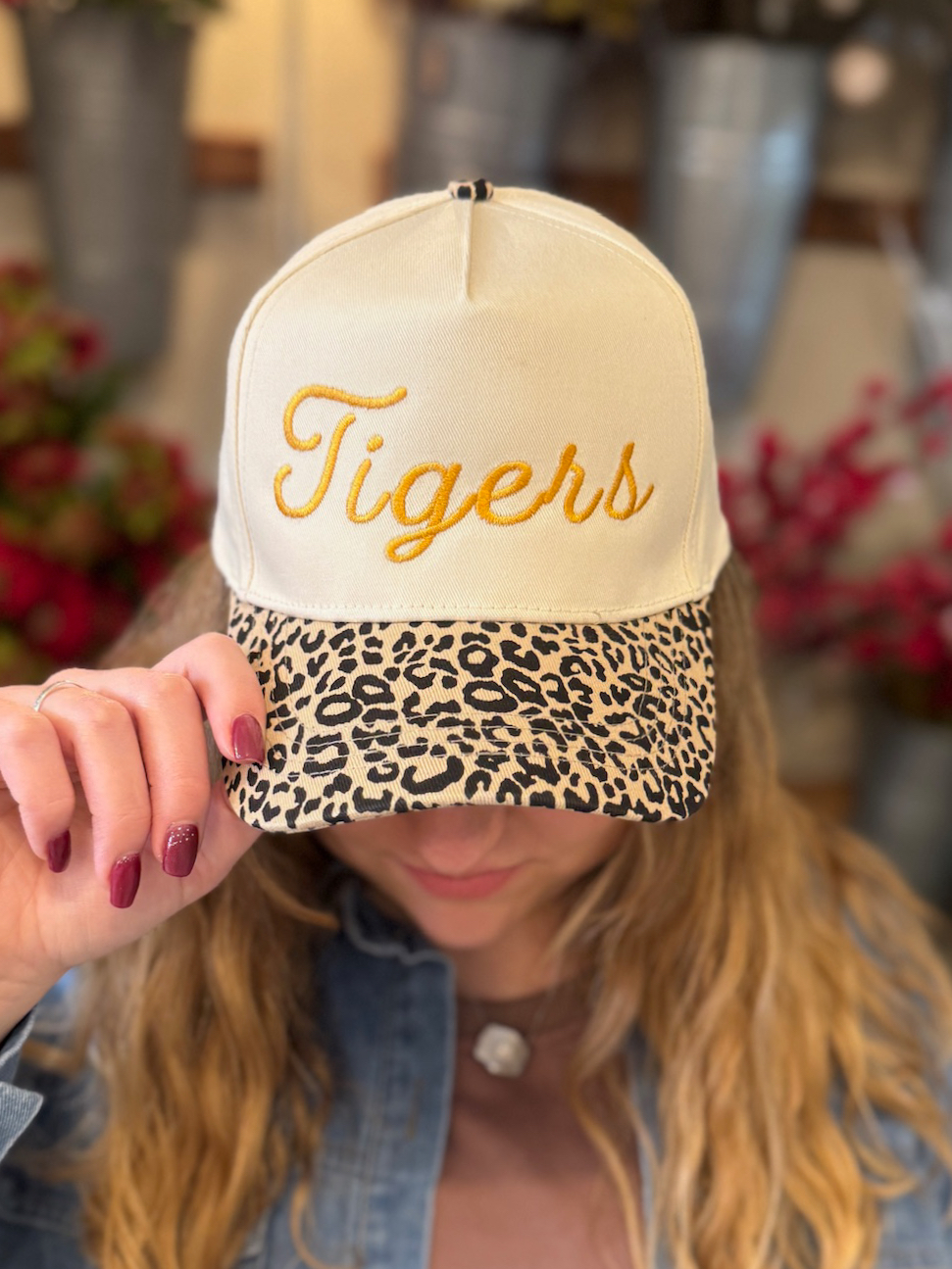 Model tipping the brim of a Tigers embroidered trucker hat with a bold leopard-print bill.