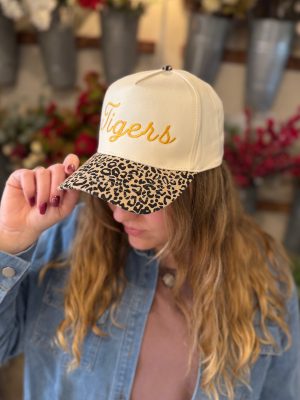 Woman wearing a natural-colored Tigers embroidered trucker hat with a leopard-print bill, styled with a denim jacket.