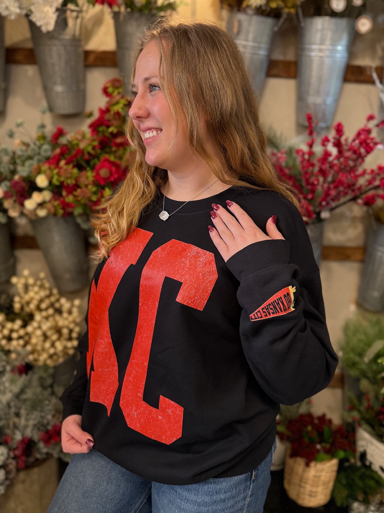 Model smiling in black KC crewneck paired with denim for casual game-day style.