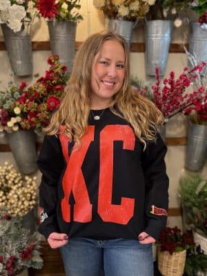 Close-up of KC crewneck showing distressed red KC print on black sweatshirt.