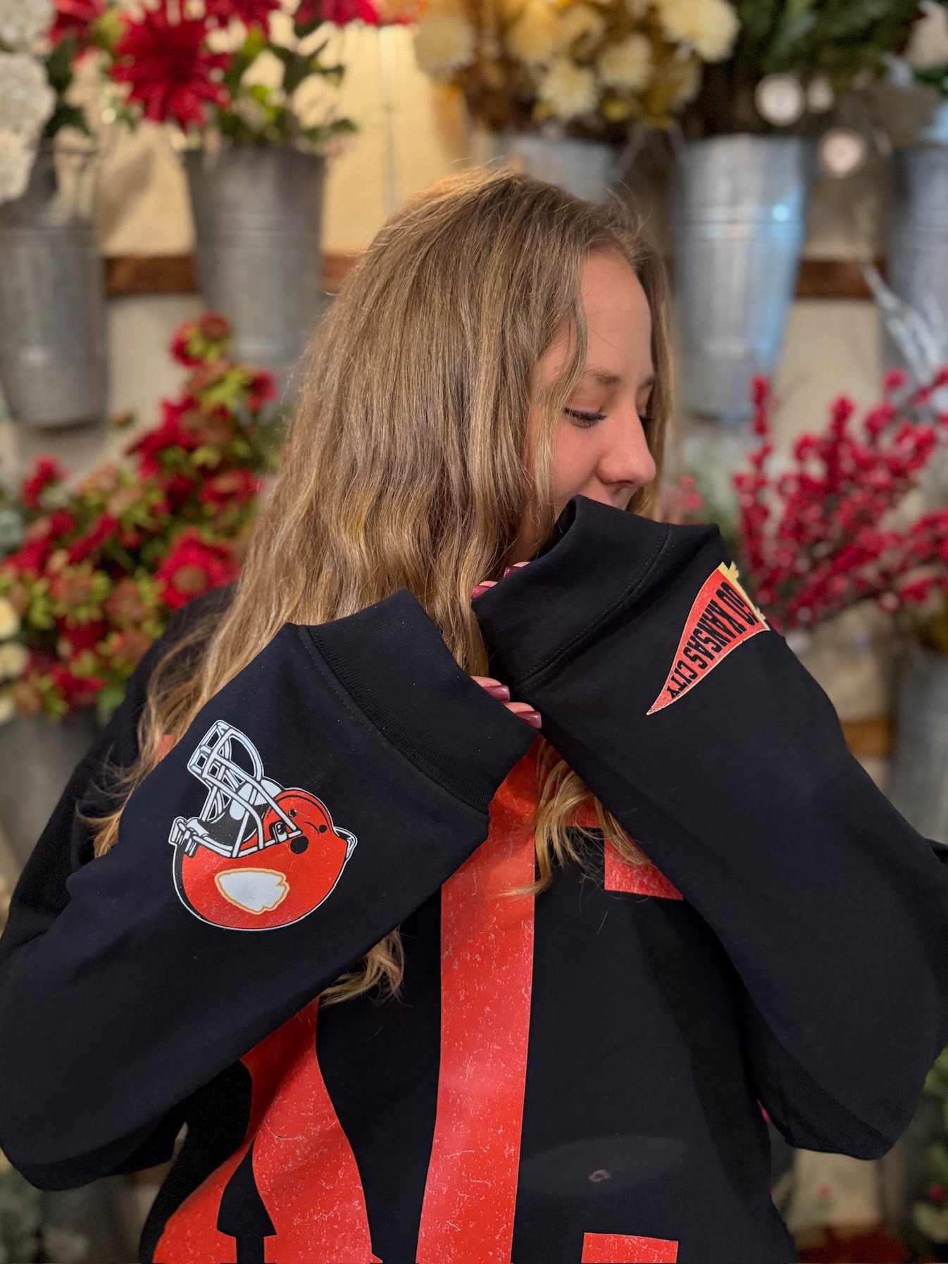 Model wearing black KC crewneck with oversized red KC lettering and Chiefs sleeve icons.