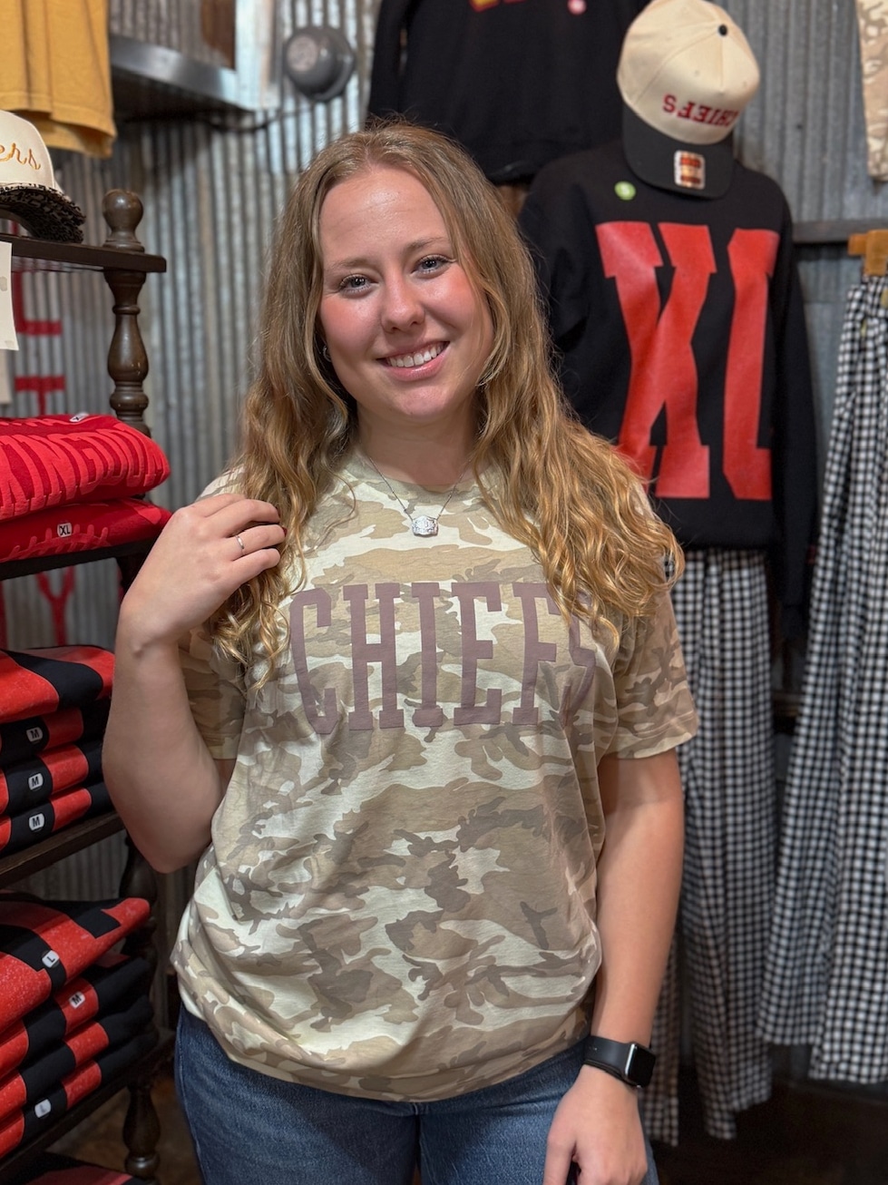 Model smiling in relaxed-fit natural camo CHIEFS tee styled casually for game day.