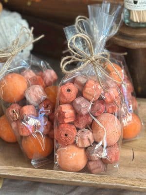 Two bags of natural dried pumpkin-shaped bowl filler in earthy orange tones tied with twine bows.