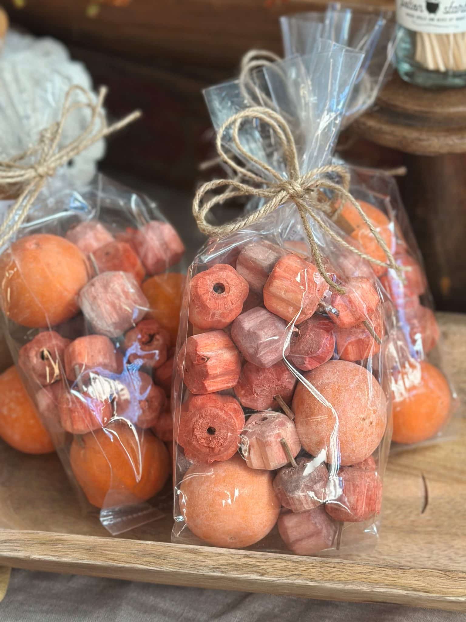be-made-hays-ks-fall-bowl-filler-pumpkin-mix Two bags of natural dried pumpkin-shaped bowl filler in earthy orange tones tied with twine bows.