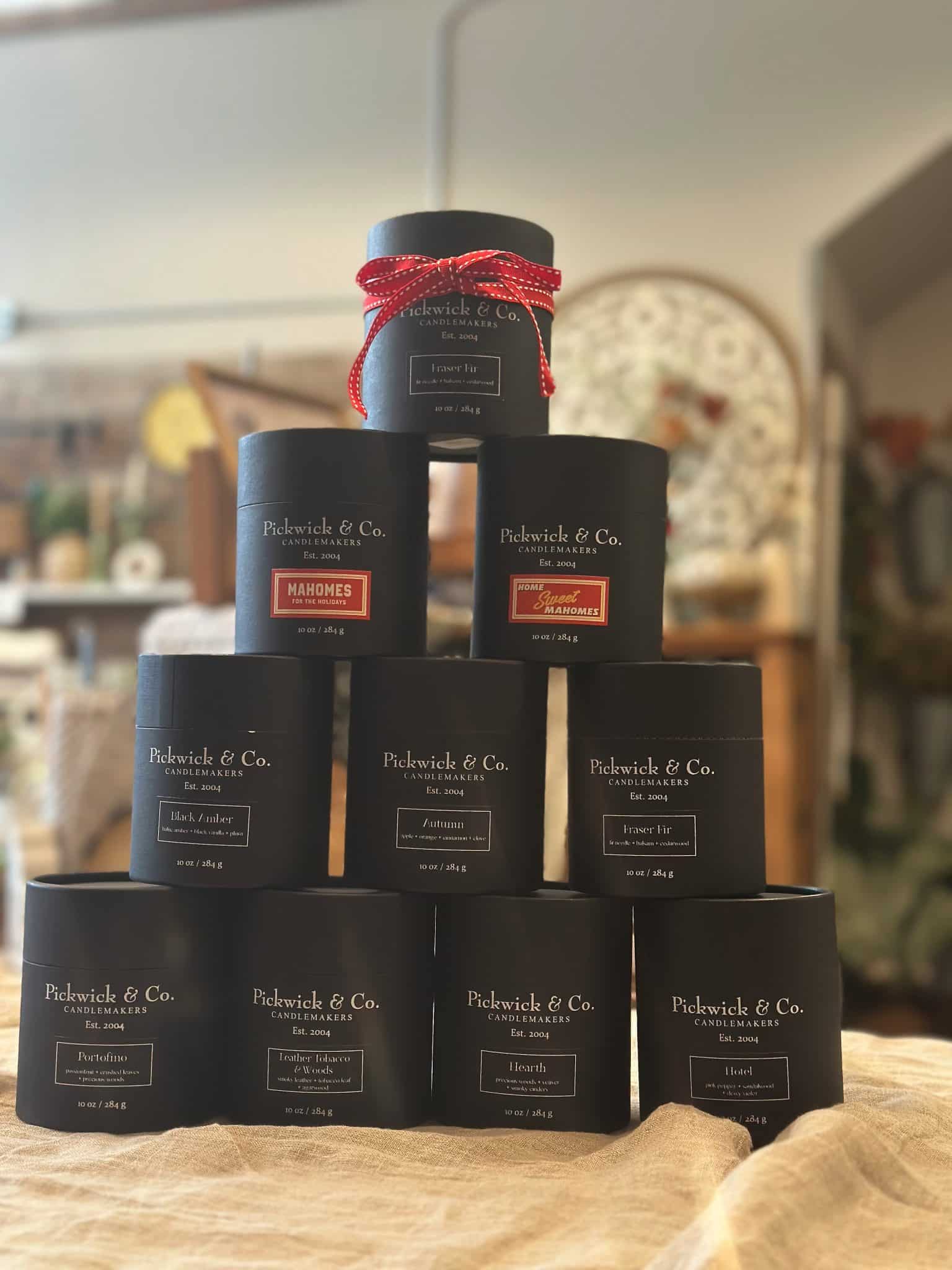 Stacked black Pickwick & Co. candle boxes in multiple scents displayed in a shop setting.