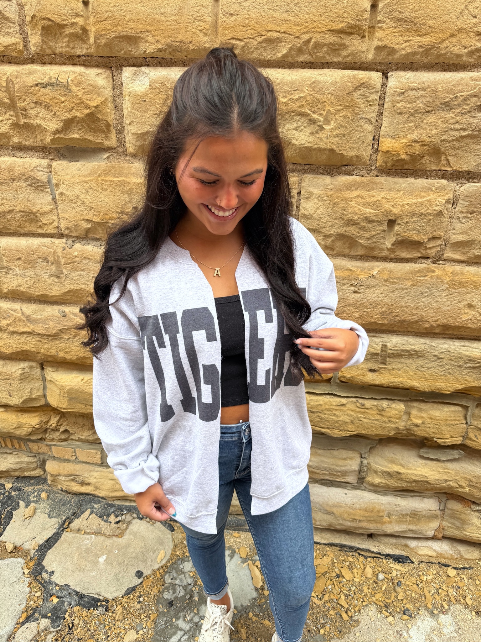 Woman wearing Tigers Oversized Ash Gray Cardigan with bold block lettering, styled with jeans and a black top.