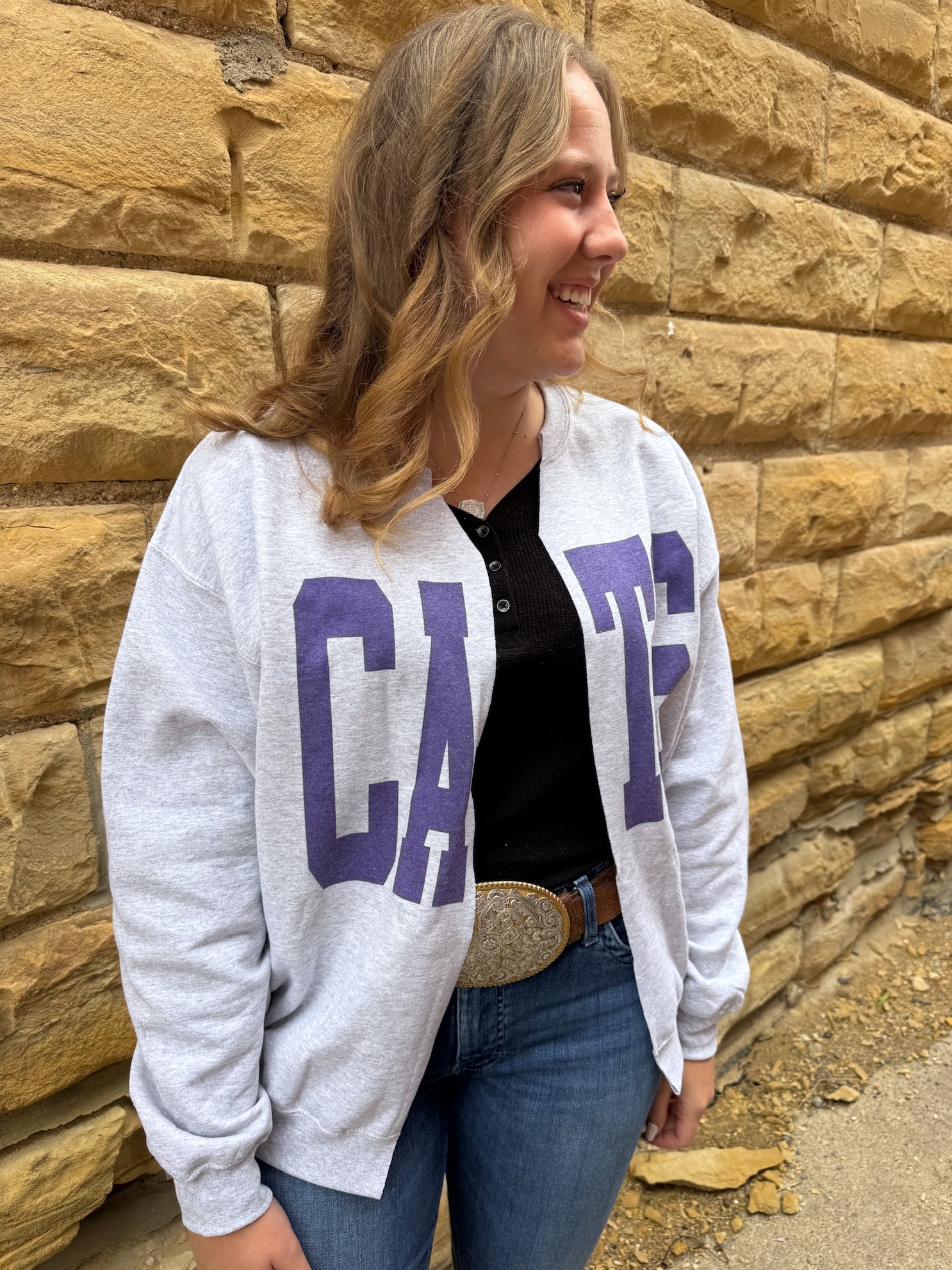 Woman wearing The Cats Oversized Ash Gray Cardigan with bold purple block lettering, styled casually with jeans.