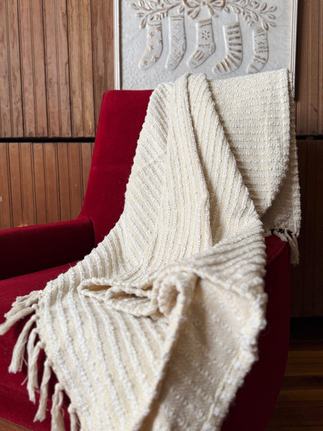 be-made-hays-ks-cream-gold-glitter-throw-blanket Cream with Gold Glitter Throw Blanket draped over a red accent chair, showing soft cream stripes, subtle gold shimmer, and fringe edges.