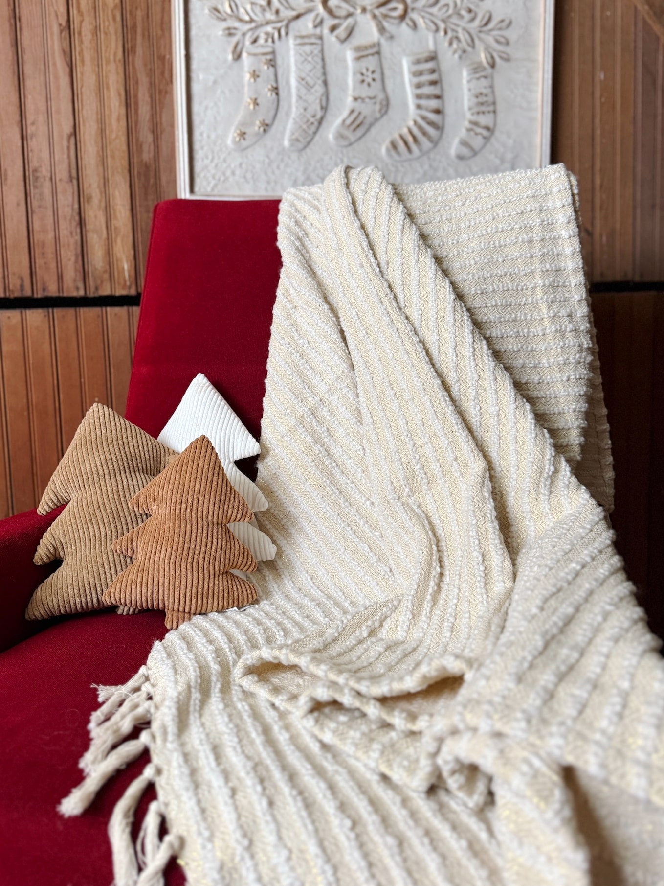 Cream with Gold Glitter Throw Blanket draped over a red chair with three neutral corduroy stuffed tree pillows styled beside it.