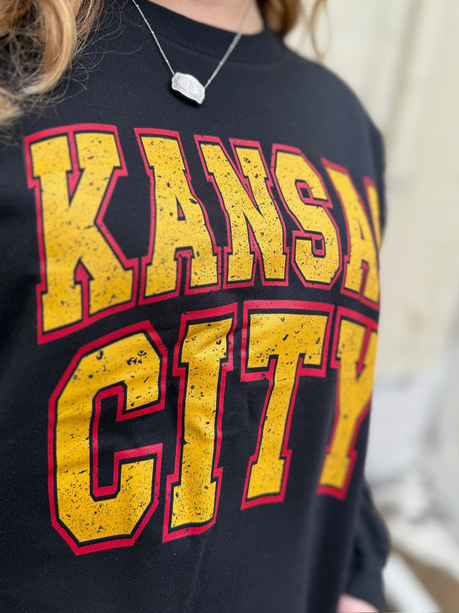 Close-up of Kansas City Block Crewneck showcasing distressed gold and red block lettering on black fleece.