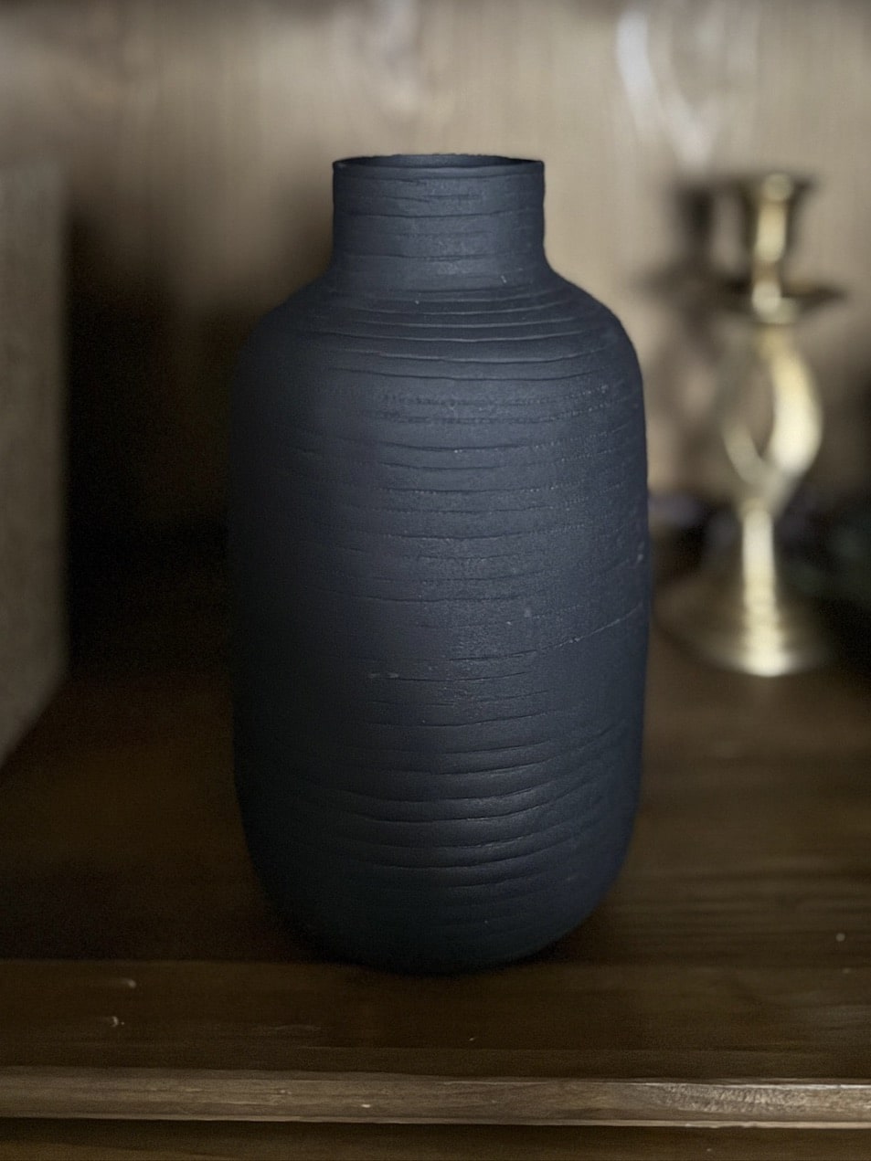 Close-up of the Textured Vase Oblong – Small in matte black, showcasing its tall, cylindrical silhouette and ridged surface detail.
