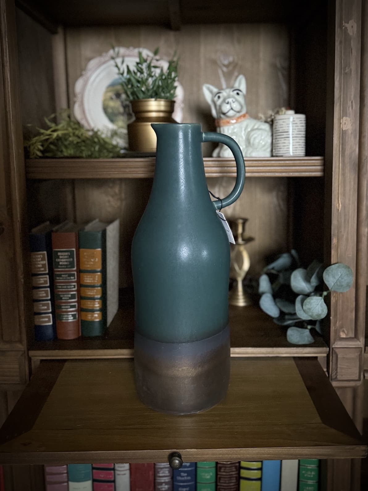 Ceramic Bronze & Emerald Pitcher Vase styled on a wooden bookshelf with books and decor accents