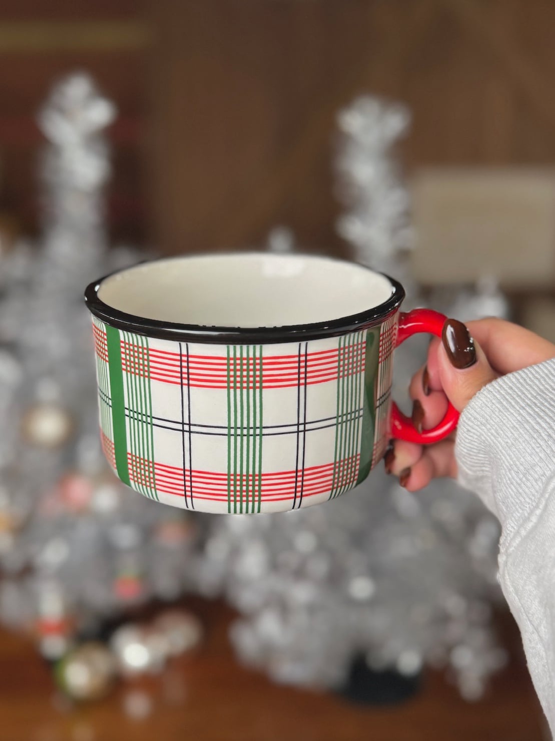 be-made-hays-ks-christmas-plaid-north-pole-mug-side-view Christmas Plaid North Pole Mug held in hand, showing red, green, and white plaid pattern with red handle and black rim.
