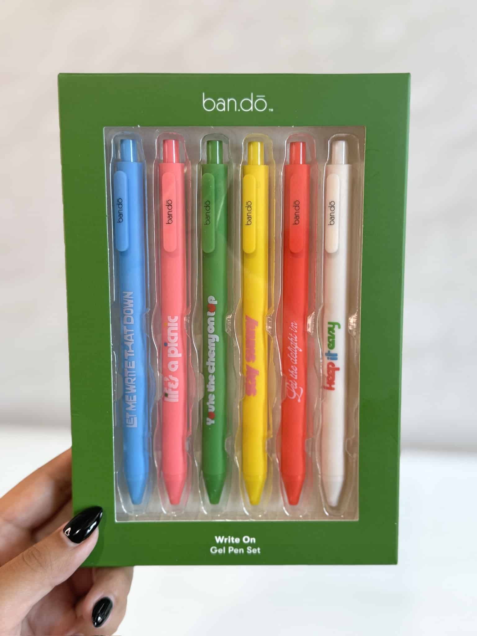 Boxed gel pen set by Ban.do featuring six rainbow pens with quotes, shown inside green packaging.