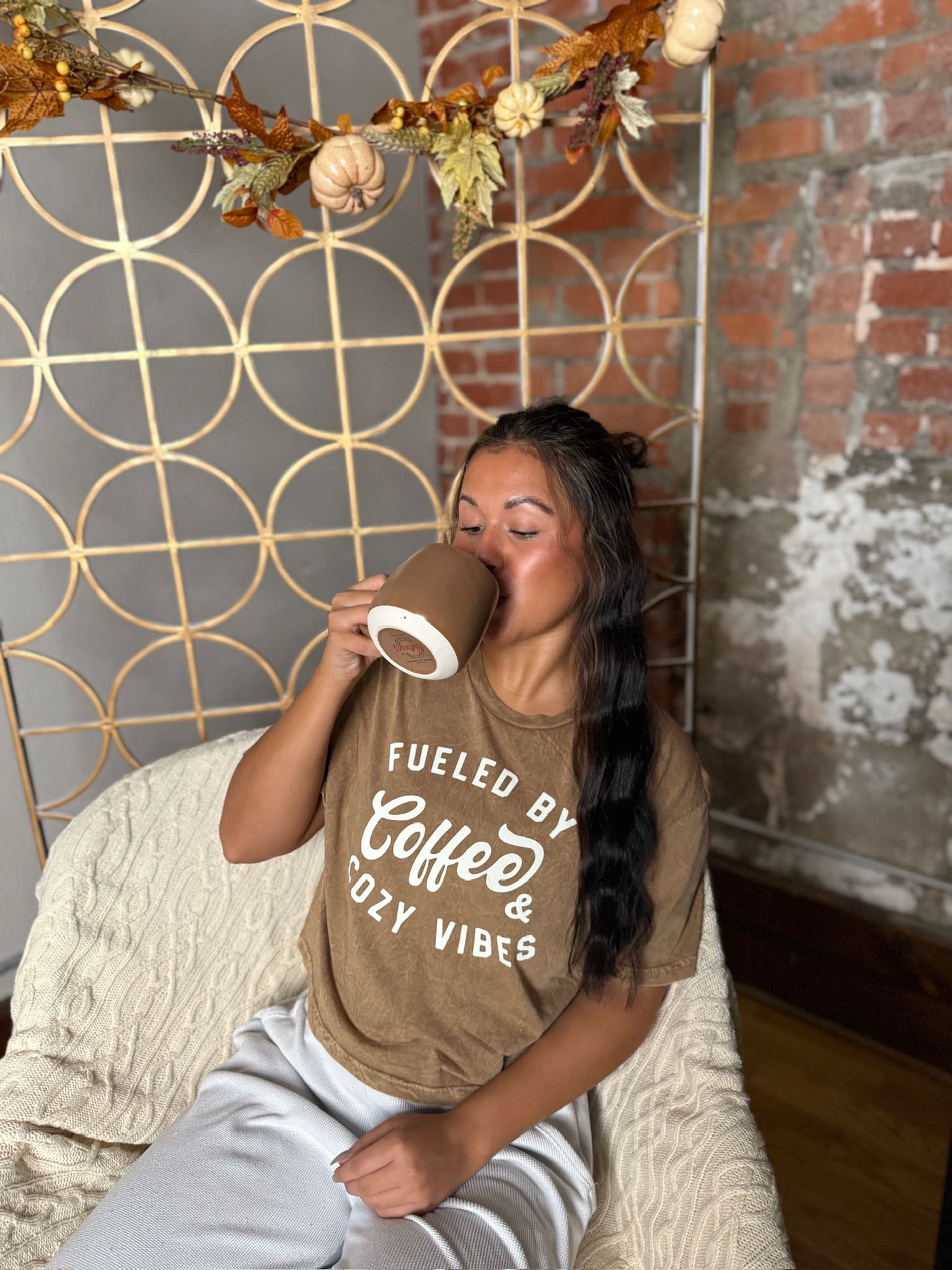 Cropped toast tan graphic tee with “Fueled by Coffee & Cozy Vibes” script in white.