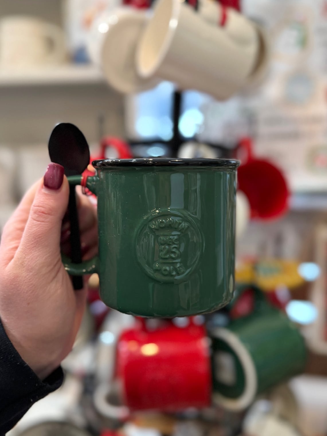 be-made-hays-ks-santa-certified-green-mug-front Front view of green “Santa Certified” ceramic mug with embossed stamp and spoon in handle.