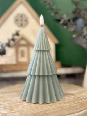 Green 3D tree flameless candle with pleated tiered layers shown in a close-up on a wooden surface.