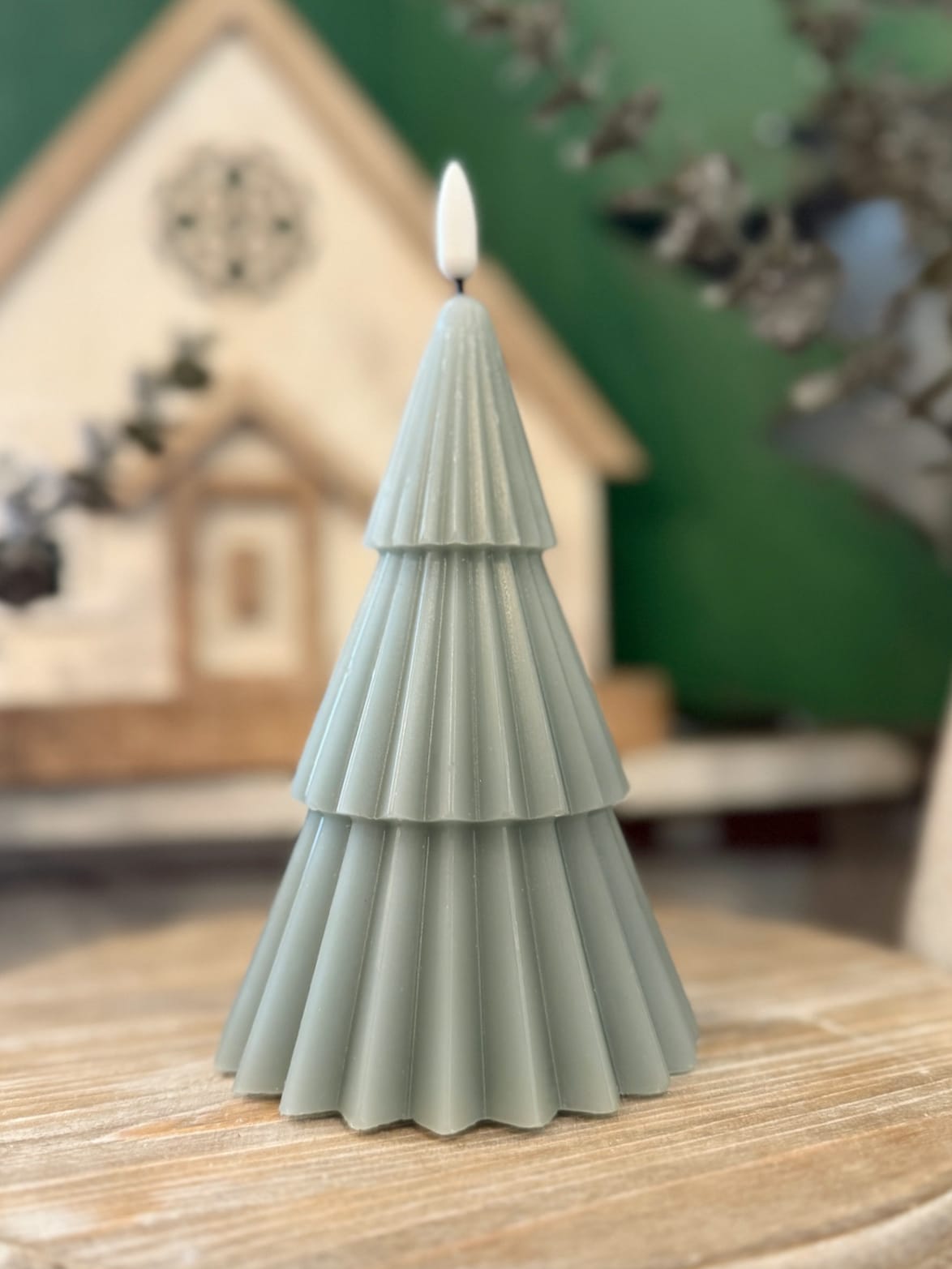 be-made-hays-ks-green-3d-tree-flameless-candle–7in-closeup Green 3D tree flameless candle with pleated tiered layers shown in a close-up on a wooden surface.