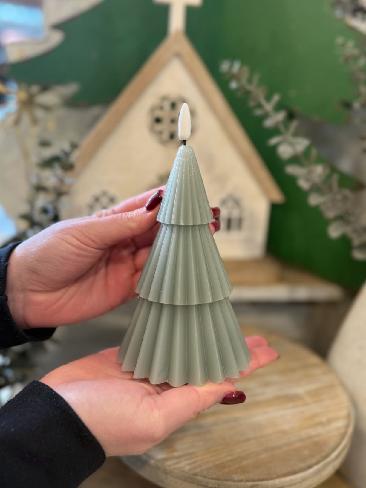 Hands holding the Green 3D Tree Flameless Candle – 7″, showing its pleated tiered design.
