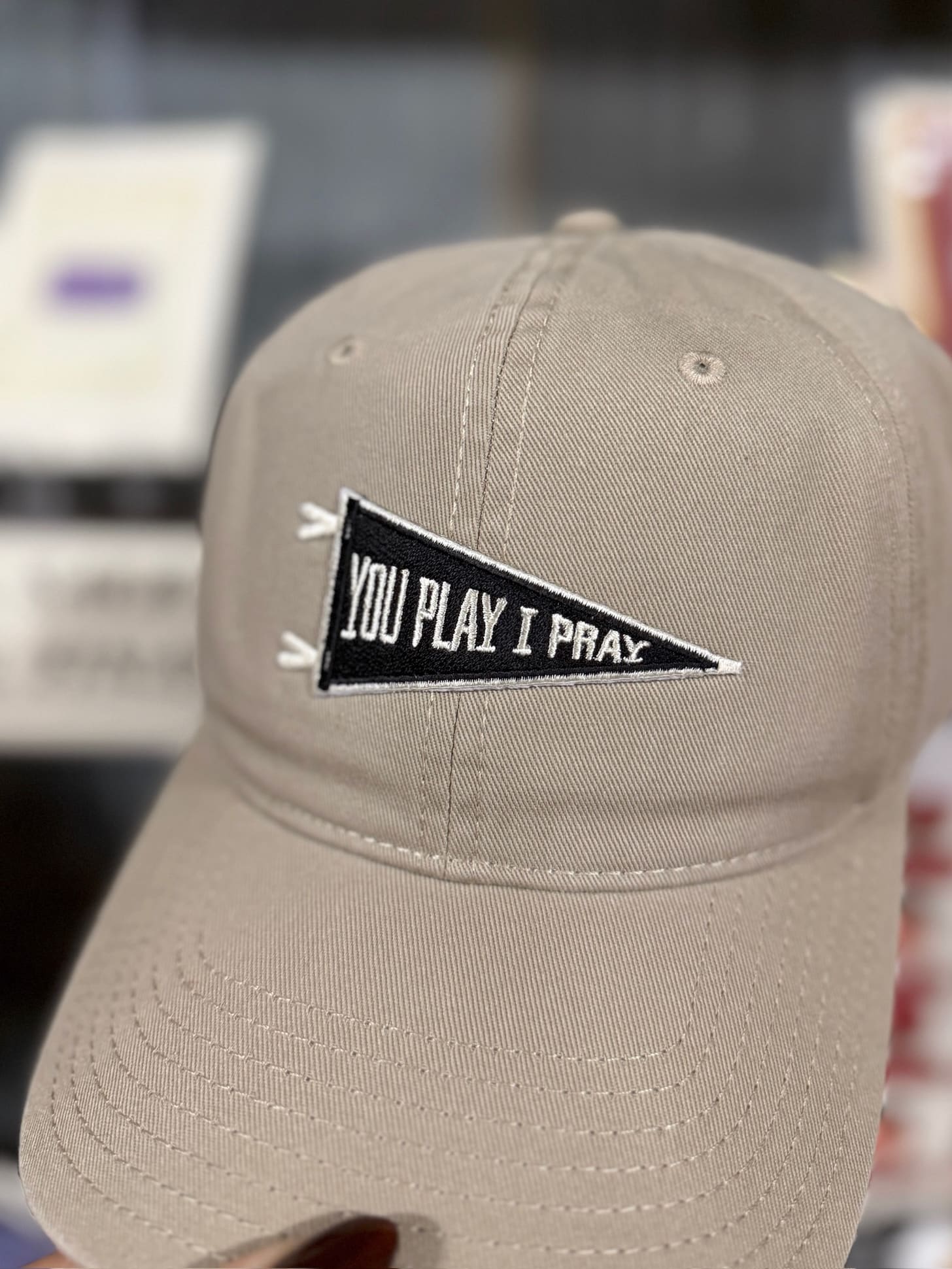 Tan baseball cap with “You Play I Pray” pennant patch, shown at an angle