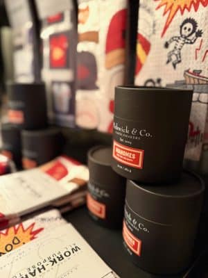 Pickwick & Co. Mahomes for the Holidays candle in sleek black packaging displayed with festive kitchen towels and gifts, featuring the signature red label.