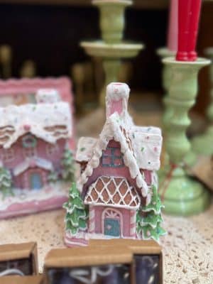 Close-up of pink gingerbread houses with snowy roofs and pastel trees.