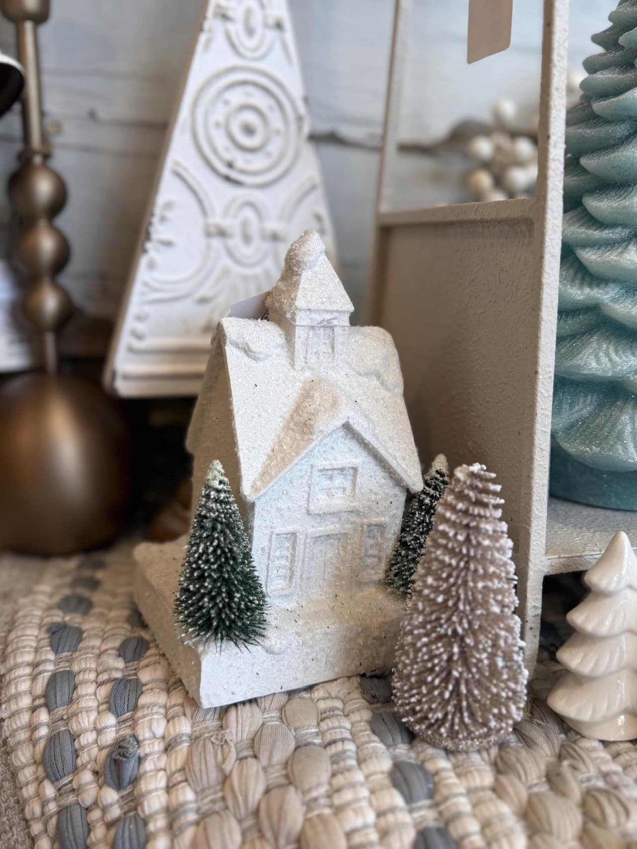 White snowy Christmas house displayed with neutral holiday décor and bottle-brush trees.